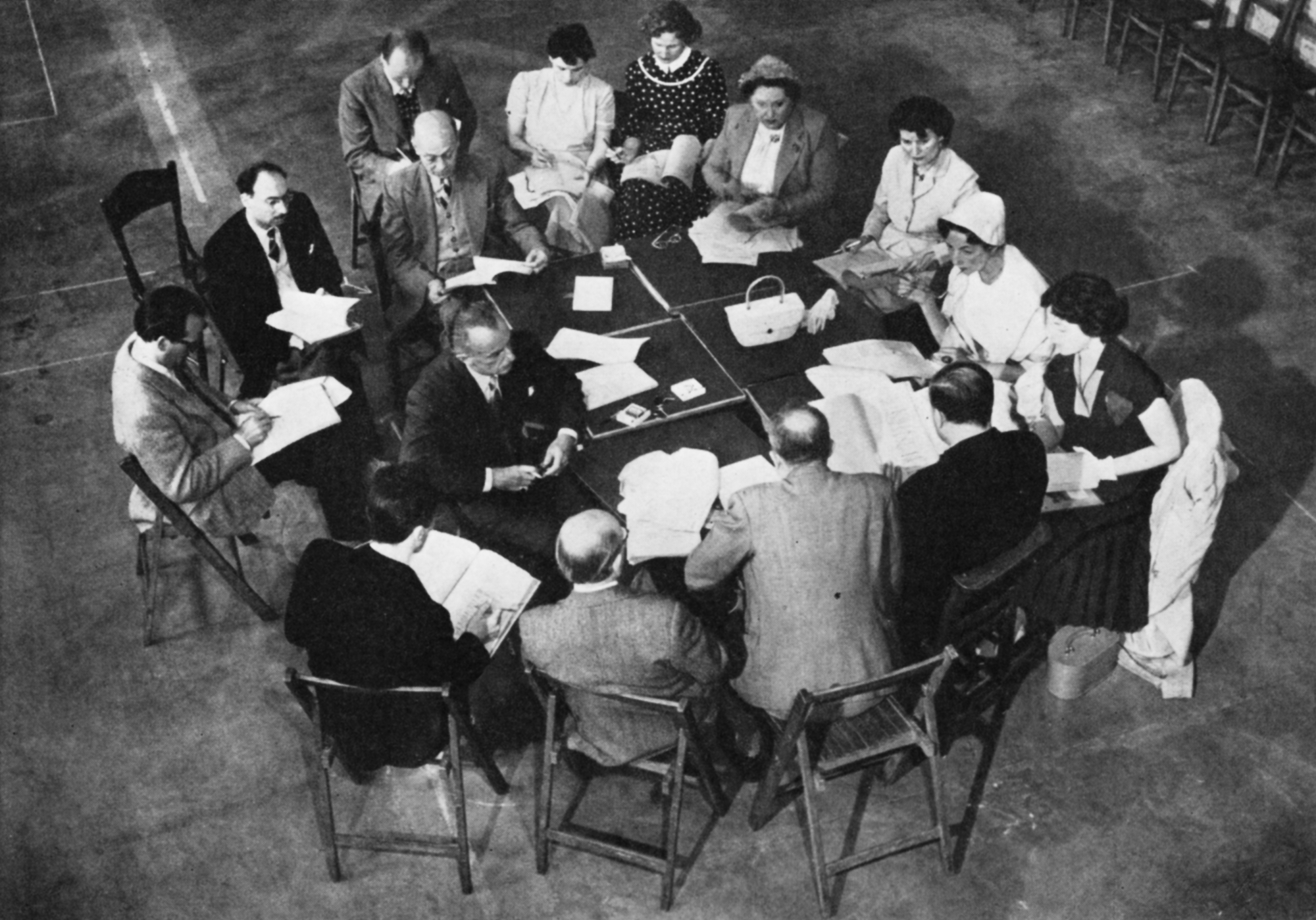 The cast sit around a large table with their scripts