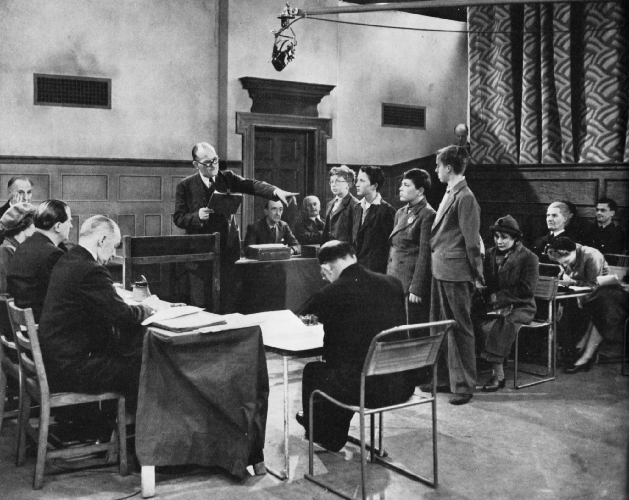 Four boys stand in front of a panel of magistrates