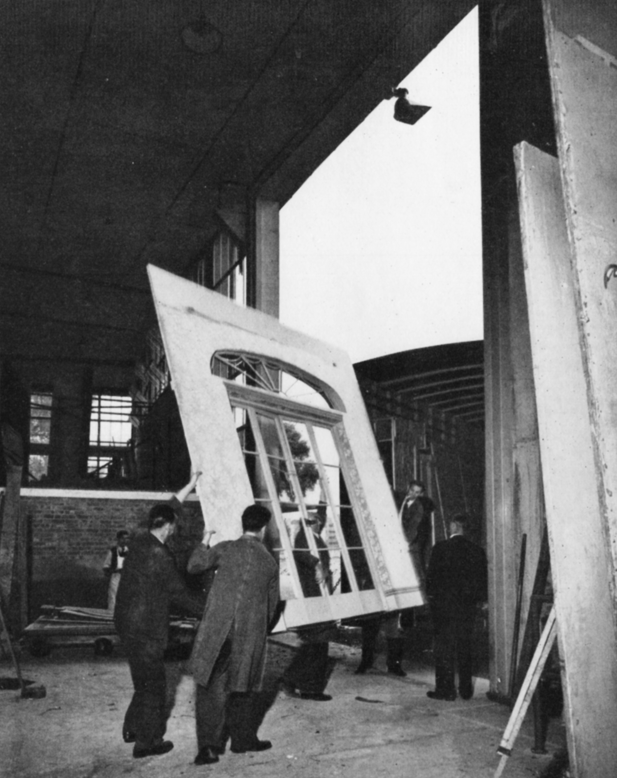 Men manoeuvre a set of French doors through the huge door of the warehouse and on to a removals van.
